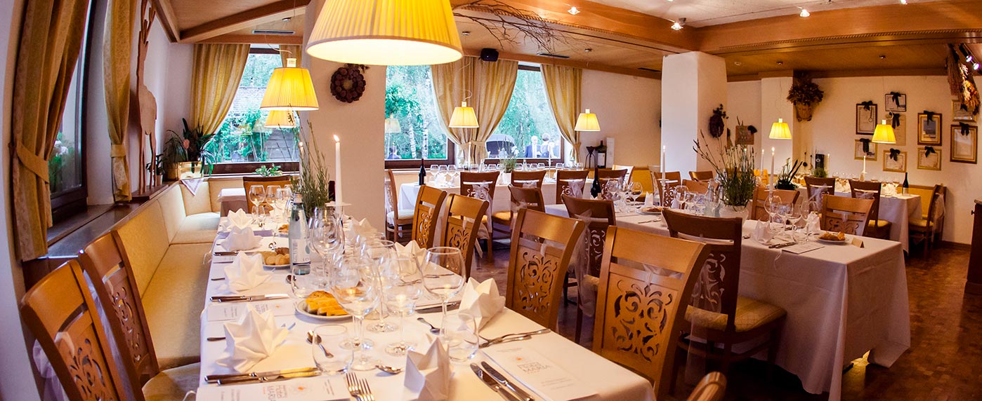 Ampia sala ristorante dell'Hotel Maria con grandi finestre, tavoli apparecchiati e sedie in legno, inondata dalla luce del mattino