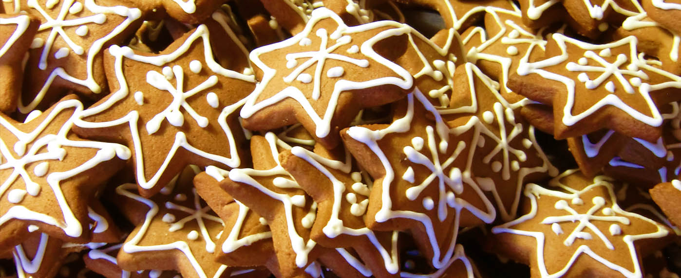 Biscotti natalizi a forma di stella decorati con glassa bianca, disposti uno sopra l’altro